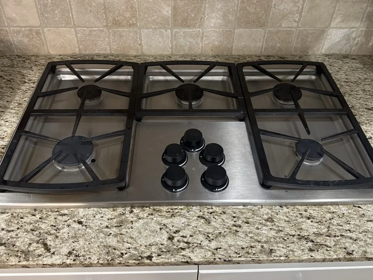 Stainless steel five-burner gas cooktop in a home kitchen