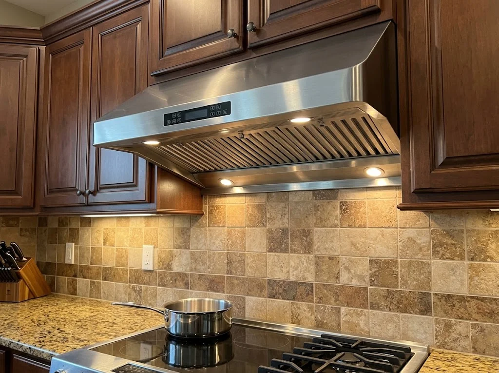 Stainless steel under-cabinet range hood above a cooktop in a home kitchen