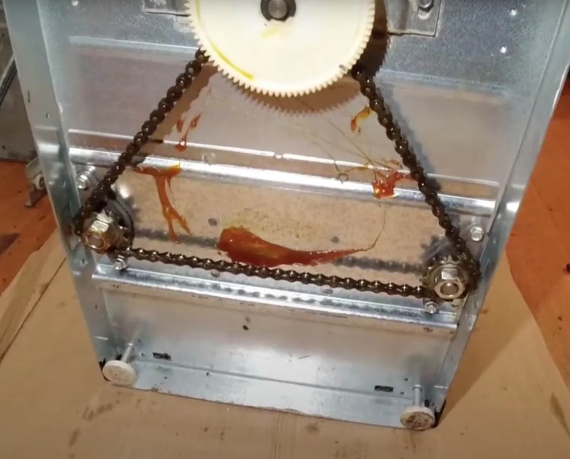 Trash compactor drive chain and gears exposed for diagnosis