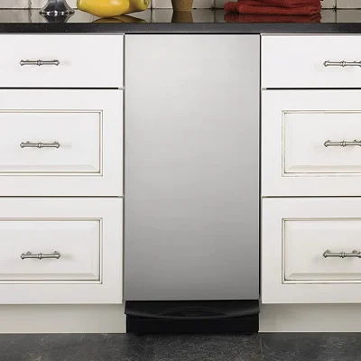 Stainless steel under-counter trash compactor in a home kitchen